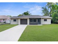 Charming single-story home featuring a well-manicured lawn and a screened-in front porch at 2444 Magellan Ave, Spring Hill, FL 34608