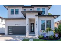 Modern two-story home with a black garage door and a landscaped front yard at 2707 W Fig St, Tampa, FL 33609