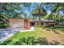 Charming single-story home featuring a brick facade, two-car garage, lush lawn, and mature trees at 495 Palmdale Dr, Oldsmar, FL 34677