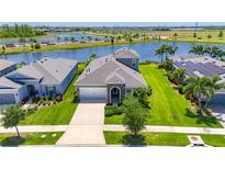 Beautiful home with well-manicured lawn and landscaping next to a scenic lake and lush greenery at 5814 Silver Sun Dr, Apollo Beach, FL 33572