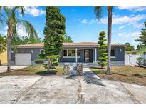 Charming single-story home featuring an inviting front porch, well-manicured lawn, and decorative landscaping at 936 Alcazar Way S, St Petersburg, FL 33705