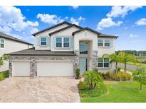 Charming two-story home featuring a stone accent, three-car garage, manicured lawn, and inviting light blue front door at 10901 Sundrift Dr, Tampa, FL 33647