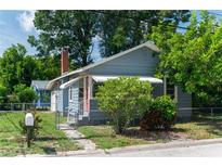 Charming bungalow with a red brick chimney, red door, and a fenced yard on a sunny day at 1716 11Th N Ave, St Petersburg, FL 33713