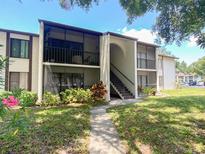 Inviting condo with screened balconies, mature landscaping, and a charming walkway to the entrance at 2643 Pine Ridge S Way # A1, Palm Harbor, FL 34684