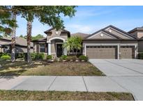 Charming single-story home with a three-car garage and beautifully landscaped front yard with stone accents at 7911 Hampton Lake Dr, Tampa, FL 33647