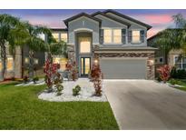 Two-story home with a two-car garage, stone accents and vibrant landscaping at 11416 Alachua Creek Ln, Riverview, FL 33579