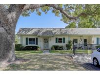 Charming home featuring green shutters, a well-manicured lawn, and a lovely wreath on the front door at 1430 Normandy Park Oaks Dr # 9, Clearwater, FL 33756