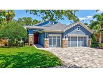 Charming blue home with a stone-accented facade, three-car garage, and a well-manicured lawn at 14727 Tudor Chase Dr, Tampa, FL 33626