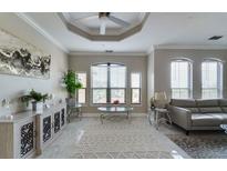 Bright living room features tray ceilings, tile floors, modern furnishings, and an abundance of natural light at 2717 Via Cipriani # 631B, Clearwater, FL 33764