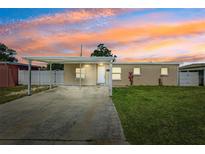 Charming single-story home featuring a covered parking area and well-maintained front yard under a colorful sunset sky at 6010 Blossom Ave, Tampa, FL 33614