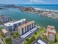 Breathtaking aerial view of waterfront condo building with boat docks, pool, and covered parking at 690 Island Way # 1011, Clearwater Beach, FL 33767
