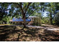 Charming stilt home featuring a quaint porch and surrounded by mature trees, offering a serene retreat at 1616 Lightfoot Rd, Wimauma, FL 33598