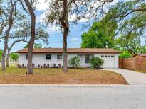 Charming single-story home featuring a well-manicured front yard, mature trees, and an attached one-car garage at 1700 25Th N St, St Petersburg, FL 33713