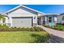 Beautiful one-story home with stone accents, gray garage door, manicured lawn and walkway to the front door at 17094 Moonflower Dr, Venice, FL 34293