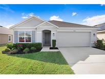 Charming single-story home with manicured lawn, gray siding, and a two-car garage at 7929 Sail Clover Ln, Zephyrhills, FL 33540