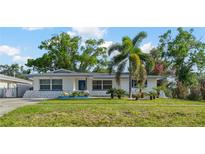 Charming home featuring a lush front lawn, palm trees, and blue trim accents enhancing curb appeal at 1099 7Th Ne Ave, Largo, FL 33770