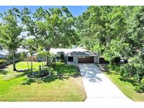 Charming home featuring a stone-accented facade, lush lawn and mature shade trees over the driveway at 1220 Pinellas Point S Dr, St Petersburg, FL 33705