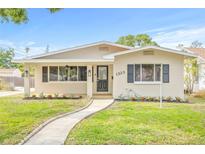 Charming single-story home features a well-manicured lawn, inviting walkway, and freshly painted exterior at 1323 48Th N Ave, St Petersburg, FL 33703