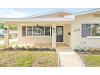 Covered front porch featuring a ceiling fan, black door, and manicured landscaping at 1323 48Th N Ave, St Petersburg, FL 33703
