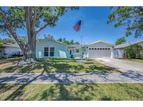 Charming, light-blue single-story home with well-maintained lawn and an American flag waving in the front yard at 14984 Cromwell Dr, Clearwater, FL 33764