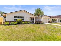 Charming single-story home featuring a palm tree, attached garage, and beautifully landscaped front yard at 3544 Edenwood Dr, Holiday, FL 34691