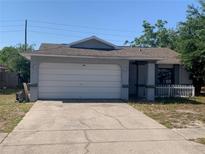 Charming single-story home features a light gray exterior, white garage door, and a classic white picket fence at 8518 Huntsman Ln, Port Richey, FL 34668