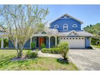 Charming blue two-story home featuring a welcoming front porch, well-manicured landscaping, and a two car garage at 9303 Alice Ln, Riverview, FL 33578