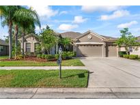 Charming single-story home with a three-car garage, a manicured lawn, and mature landscaping under a blue sky at 10517 Palm Cove Ave, Tampa, FL 33647