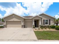 Charming single-story home with a three-car garage, stone accents, and a well-manicured lawn at 13637 Blythewood Dr, Spring Hill, FL 34609