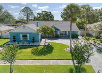 Charming blue home features a manicured lawn, paver driveway, and lush landscaping for great curb appeal at 16605 Round Oak Dr, Tampa, FL 33618