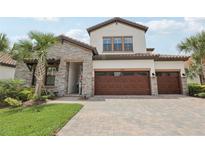 Elegant two-story home featuring a paver driveway, stone accents, and a spacious three-car garage at 21746 Amelia Rose Way, Land O Lakes, FL 34637