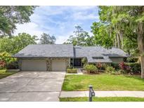 Charming single-story home features a gray stone front, beautiful landscaping, and an attached two car garage at 3138 Edgemoor Dr, Palm Harbor, FL 34685