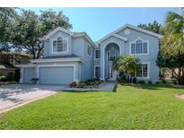 Charming two-story home with lush green lawn, landscaped yard, and a light blue exterior at 4063 Ligustrum Dr, Palm Harbor, FL 34685