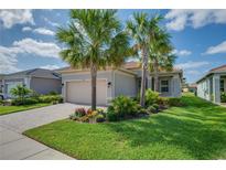 Beautiful single-story home featuring a paver driveway, two-car garage, and lush landscaping with palm trees at 4931 Sevilla Shores Dr, Wimauma, FL 33598
