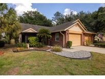 Charming brick home featuring an attached two-car garage and a beautifully landscaped front yard at 6438 Brentwood Dr, Zephyrhills, FL 33542