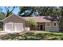 Charming single-story home featuring a two-car garage, landscaped yard, and a classic front entrance at 6994 Fort King Rd, Zephyrhills, FL 33541