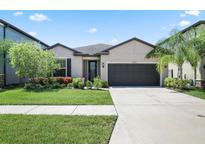 Charming single-story home featuring a two-car garage, well-maintained lawn and landscaped garden at 9309 Tradewater Oaks Ct, Riverview, FL 33578