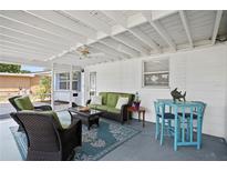 Inviting screened porch with wicker furniture, a ceiling fan, and bright decor at 10442 Cirimoya Ln, Seminole, FL 33772