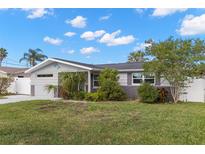 Charming single-story home featuring a well-maintained lawn, tropical landscaping, and a stylish dolphin accent at 13704 Evelane Dr, Hudson, FL 34667