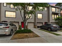 Three-story townhome showcasing a well-maintained exterior with individual garages and a vibrant red front door at 2547 Lexington Oak Dr, Brandon, FL 33511