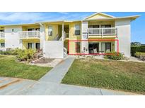 Yellow and white condo with a small patio area accessible from the main floor at 455 Alt 19 S # 65, Palm Harbor, FL 34683