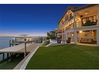Elegant backyard with a private dock, luxury pool, manicured lawn, and an entertainment area overlooking the water at 5939 Bayview S Cir, Gulfport, FL 33707