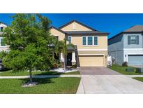 Charming two-story home with a tan exterior, well-manicured lawn, and inviting curb appeal at 13651 Ashlar Slate Pl, Riverview, FL 33579