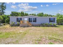 Charming single-story home features a well-maintained lawn and a welcoming front entrance with a wooden porch and stairs at 25126 Huston St, Brooksville, FL 34601