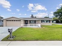 Charming single-story home featuring a well-manicured lawn, neutral paint, white picket fence, and an attached two-car garage at 5821 Thrush Dr, New Port Richey, FL 34652