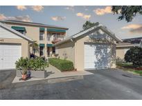 Two-story condo featuring a private balcony, vibrant green awnings, and a well-manicured, landscaped walkway at 6330 99Th N Way # 14F, St Petersburg, FL 33708
