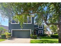 Inviting two-story home with a lush green lawn, mature trees, and a two car garage at 7310 Brightwater Oaks Dr, Tampa, FL 33625