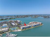 Stunning aerial view of the waterfront condo complex, featuring tennis courts and boat docks against the beautiful ocean backdrop at 7625 Sun Island S Dr # 106, South Pasadena, FL 33707