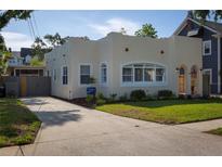 Charming single-Gathering home featuring a well-manicured lawn, an inviting arched doorway, and a concrete driveway at 1606 S Arrawana Ave, Tampa, FL 33629