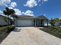 Charming single-story home featuring a paver driveway, two car garage, and covered front porch at 17093 Moonflower Dr, Venice, FL 34293